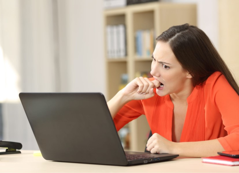 Person sitting in front of laptop biting finger